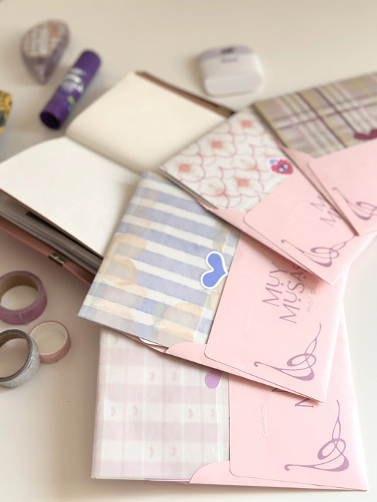 Cartas y sobres rosas de Muy Musas Mail Club junto a papeles estampados y materiales de papelería creativa.
